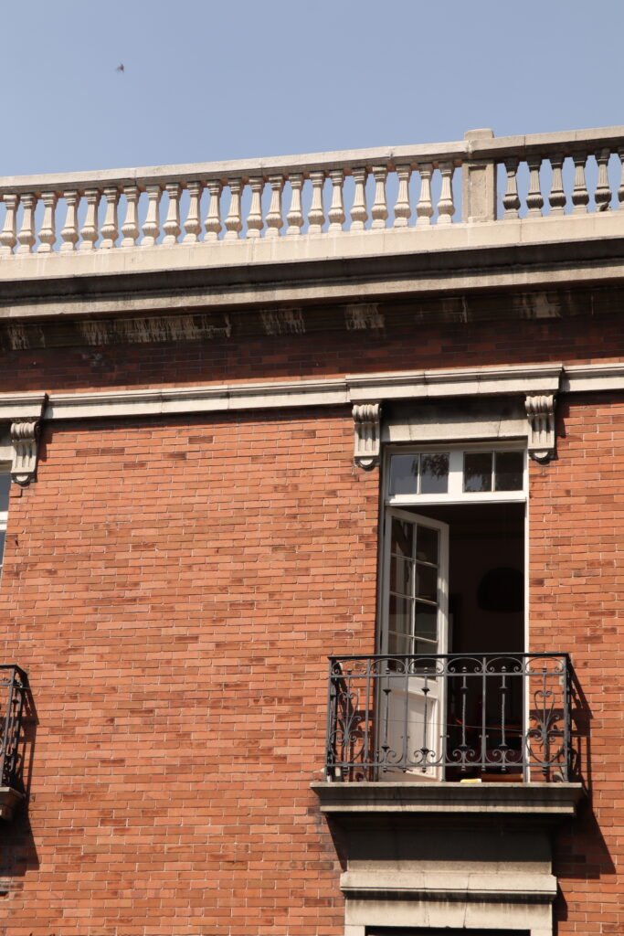 edificio de ladrillo con un balcón con una ventana abierta