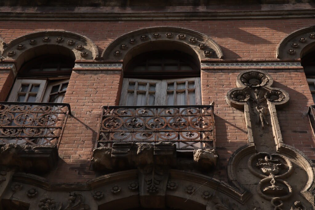 una facjada de ladrillo con balcones y una cruz de piedra